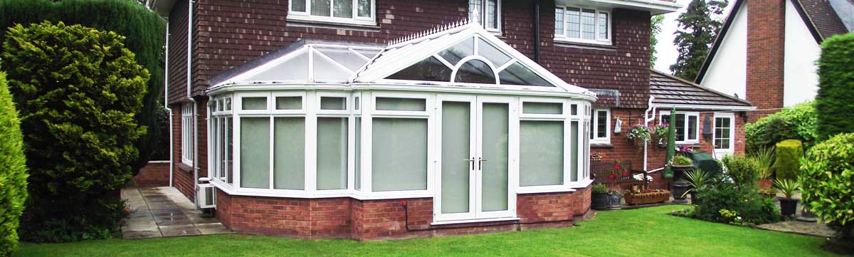 Large conservatory at rear of house with a garden scene